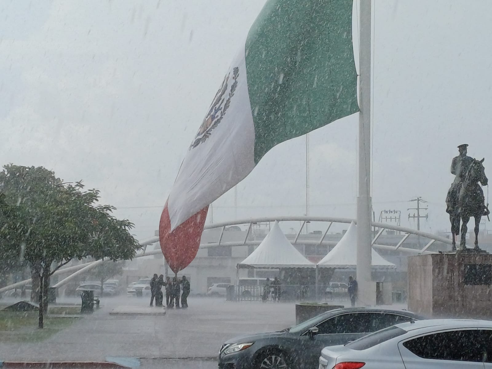 ¡Se iba a caer! Policías salvan la mega bandera bajo el aguacero